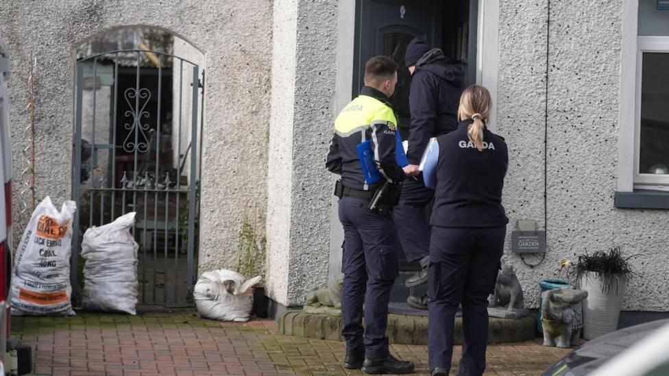 Police officers in dark clothing entering a white building