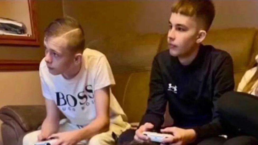 Mason Rist and Max Dixon sitting on a sofa with controllers in their hands