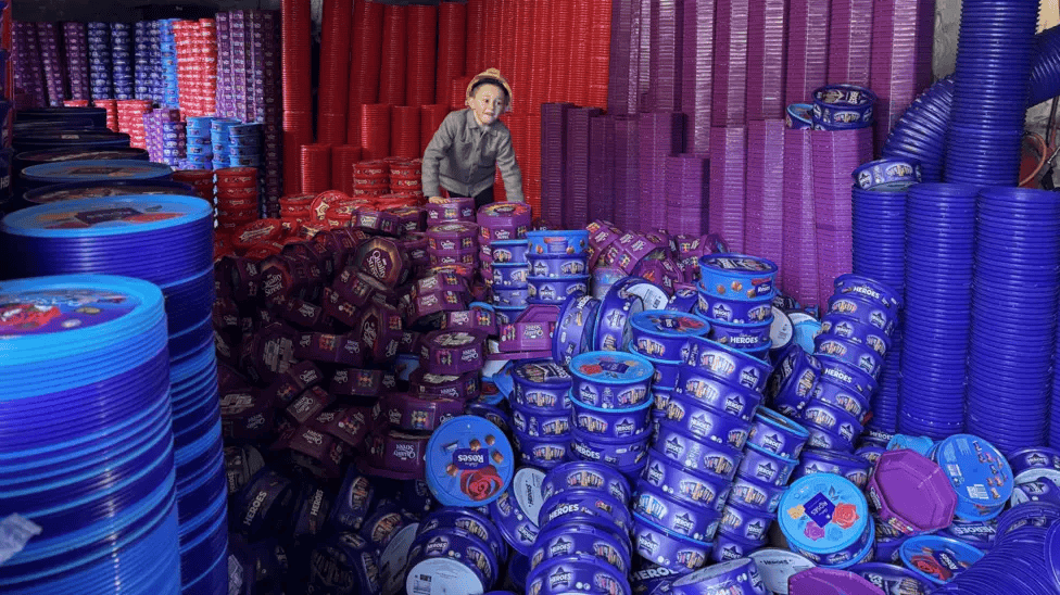 Teddy climbing through piles of red, purple and blue sweet tubs
