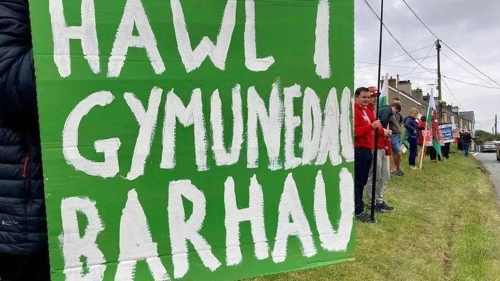 Arwydd 'Hawl i Gymunedau Barhau' yn ystod protest ynghylch y trafferthion rhai i brynu tai yn eu cymunedau eu hunain