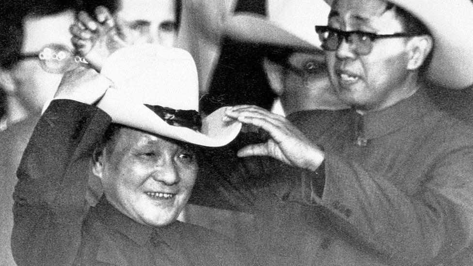 With the help of an aide, Deng Xiaoping, tries on a cowboy hat presented to him at a rodeo near Houston in 1979