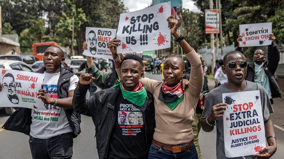 A group of protesters on a street in Nairobi march and hold up various signs - some in Swahili - calling for justice over the death of Albert Ojwang