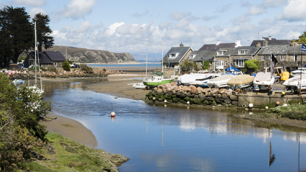 A picture of the River Soch leading to Abersoch beach on a sunny day. On the right there are boats and houses.