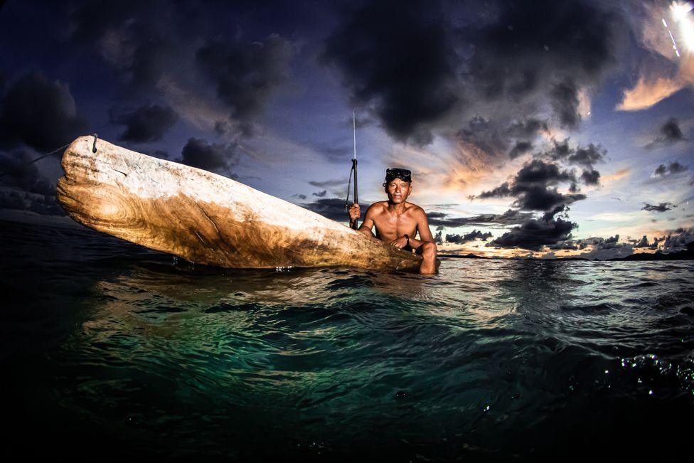 A member of the Bajau holds a fishing spear in a traditional wooden boat in
Selakan Island, Malaysia
