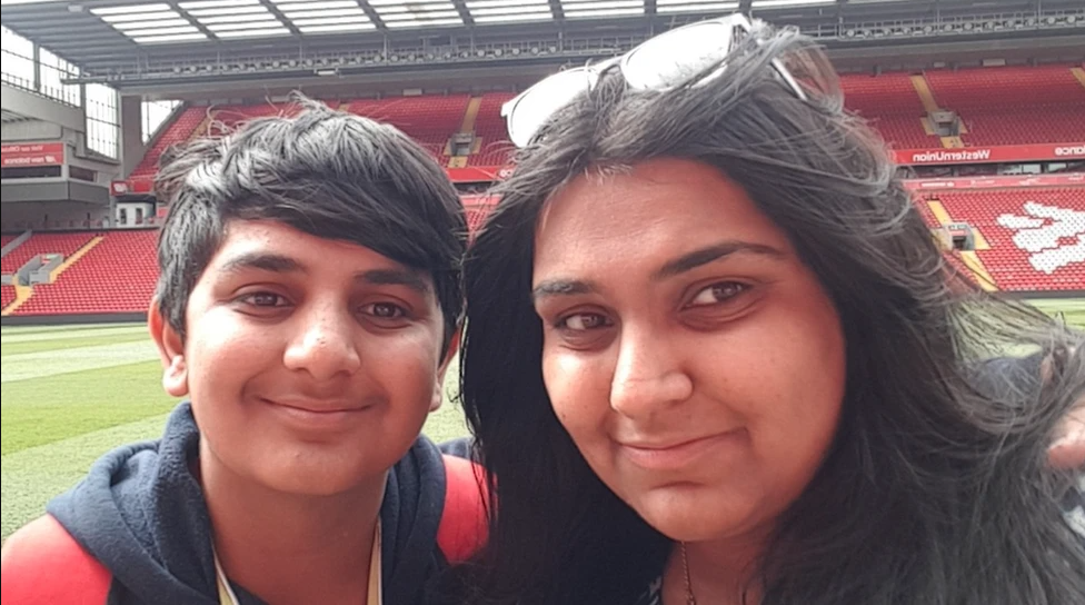 Ronan is at a football ground with his mother, Pooja. The pair are smiling in the close up shot.