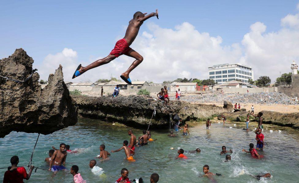 A boys jumps through the air into the sea where other children are swimming in Mogadishu, Somalia - Thursday 6 November 2025.