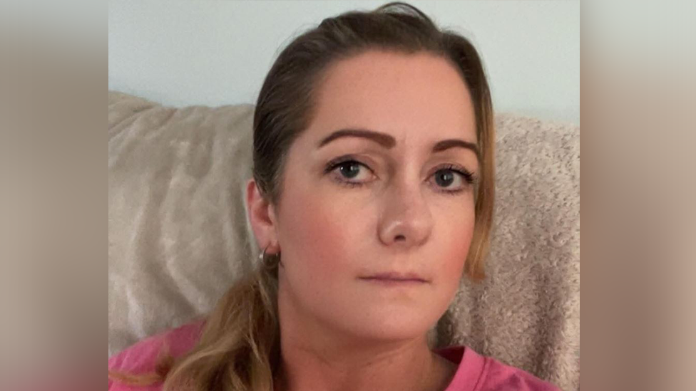 A family photo of Angela Shellis given to the police. It's a head shot with her looking at the camera. She has long blonde hair and is wearing a pink cotton top. she has hoop earrings and light make up with slim sculpted eyebrows.