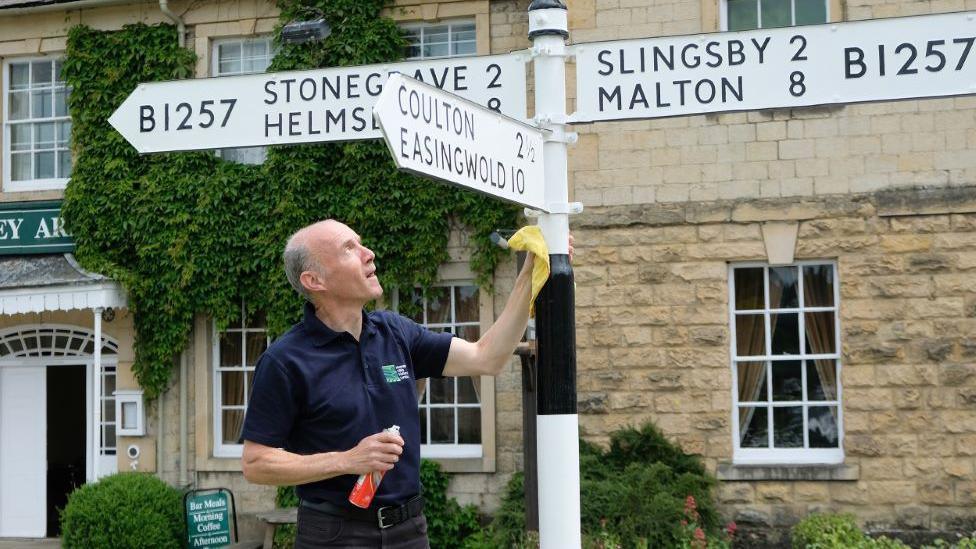 Man cleaning road direction signs