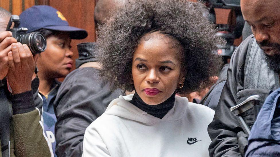 Nandipha Magudumana, in a white Nike tracksuit top, is photographed as she enters the magistrate's court surrounded by police in Bloemfontein, South Africa - August 2023.