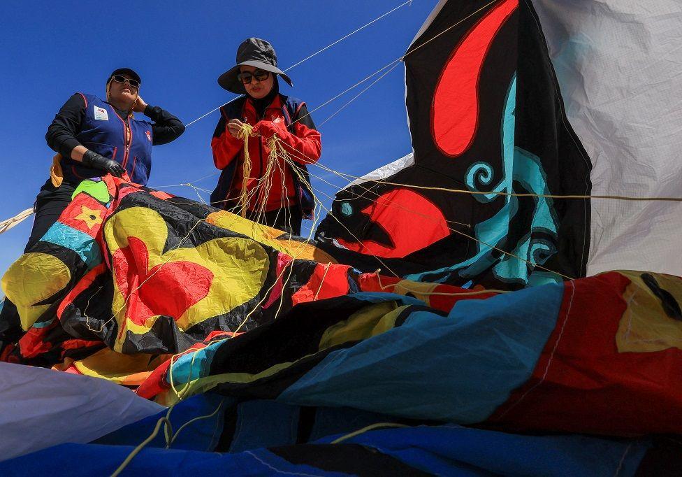 Tunisia's Afef Sebti and Amelia Amira prepare their kite at Dolphin Beach ahead of this weekend's 30th Cape Town International Kite Festival, an awareness campaign for World Mental Health Day where kite enthusiasts gather to fly colourful kites to raise funds for mental health support, in Cape Town, South Africa.