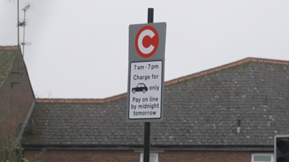 A grey and white road sign saying motorists can pay the fee "on line", instead of "online"