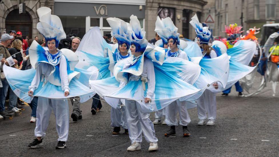 Tall ships crew members were in bright white and blue costumes in street parade.