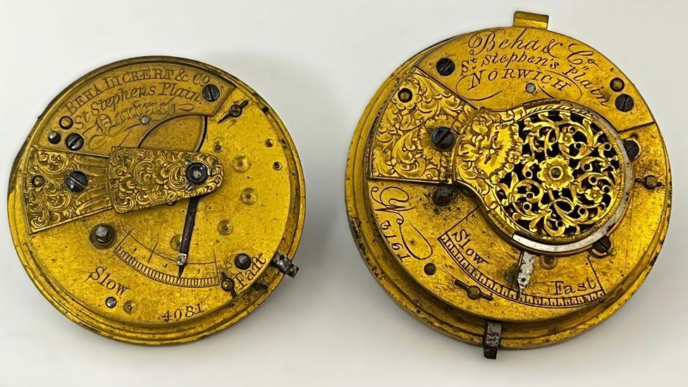 Two mid-19th Century gold-coloured watch movements. The one on the right is slightly smaller than the one on the left. The one on the right is marked Beha & Lickert & Co, St Stephens Plain, Norwich. The one on the left is marked Beha & Co, St Stephen's Plain, Norwich. They are etched with intricate designs.