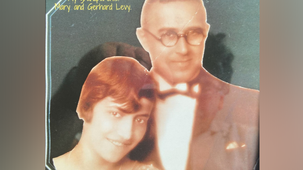 An old photo shows Mrs Levy with short red hair stood next to her husband who is wearing a smart suit and bow tie with glasses on.