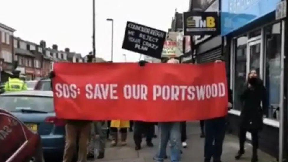 People walking on Portswood road with a red banner reading "SOS: save our Portswood"