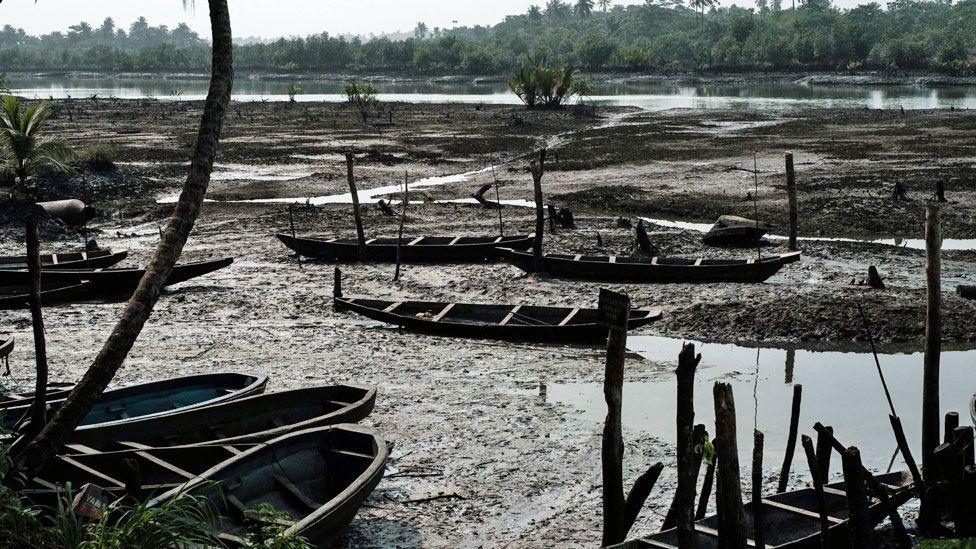 Fishing boats in Ogoniland seen smeared in oily mud by the riverside