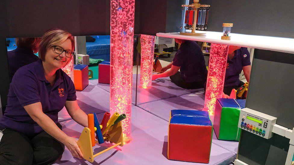 A woman holds a toy in a sensory room