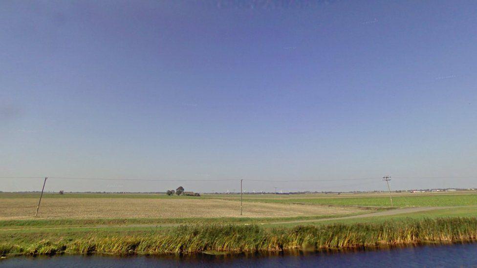 A green open field with a body of water at the front