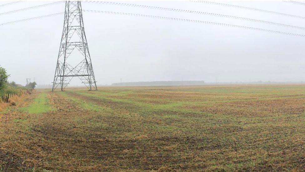 Site of the solar farm an open field with an electricity pylon in one corner