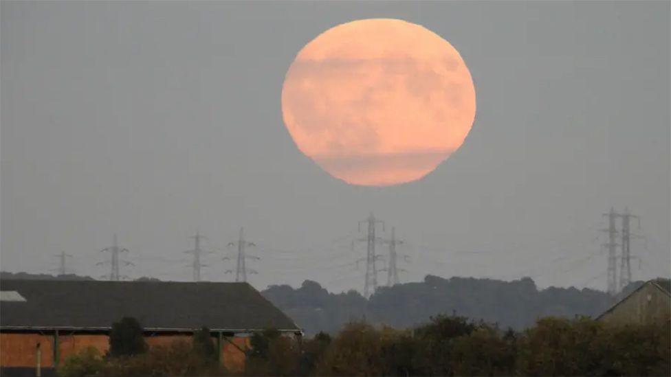 A view of September's supermoon above the town of Goole with electricity pylons underneath it 