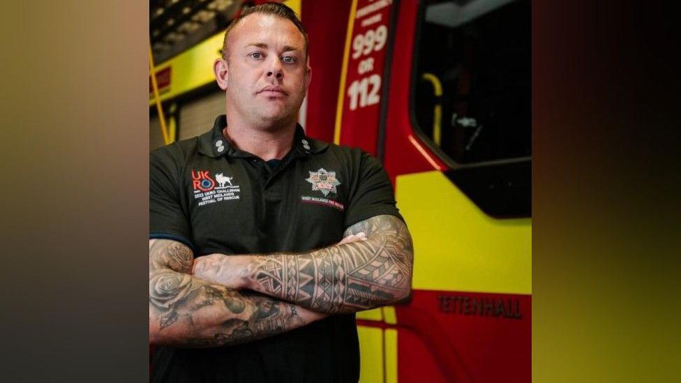 Firefighter Craig Tipton standing in front of a fire engine 