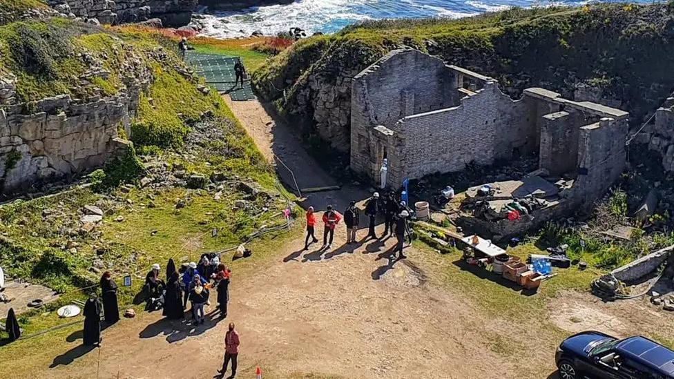 Filming taking place at Winspit Quarry. Crews are gathered around the site, with old ruins visible.