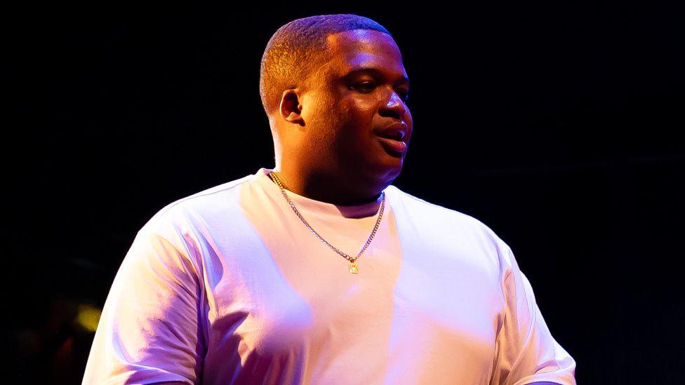 Nathan Queeley-Dennis on stage in a white T-shirt