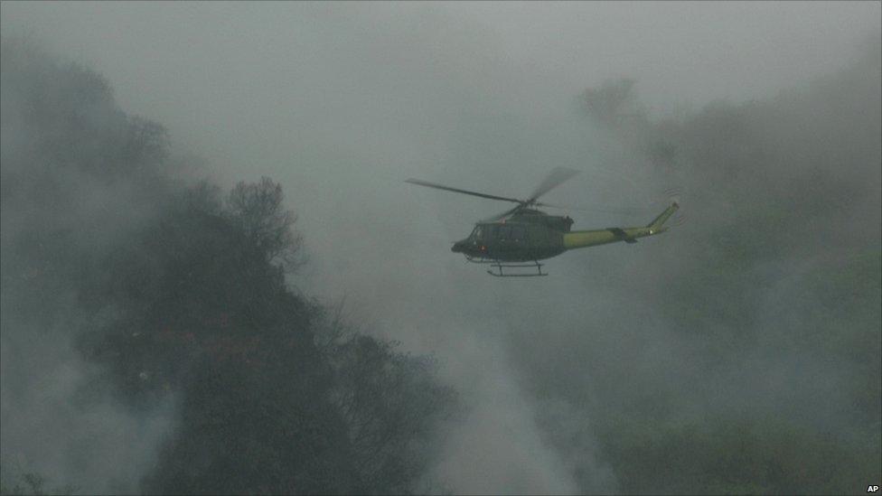 A helicopter flies over the crash site