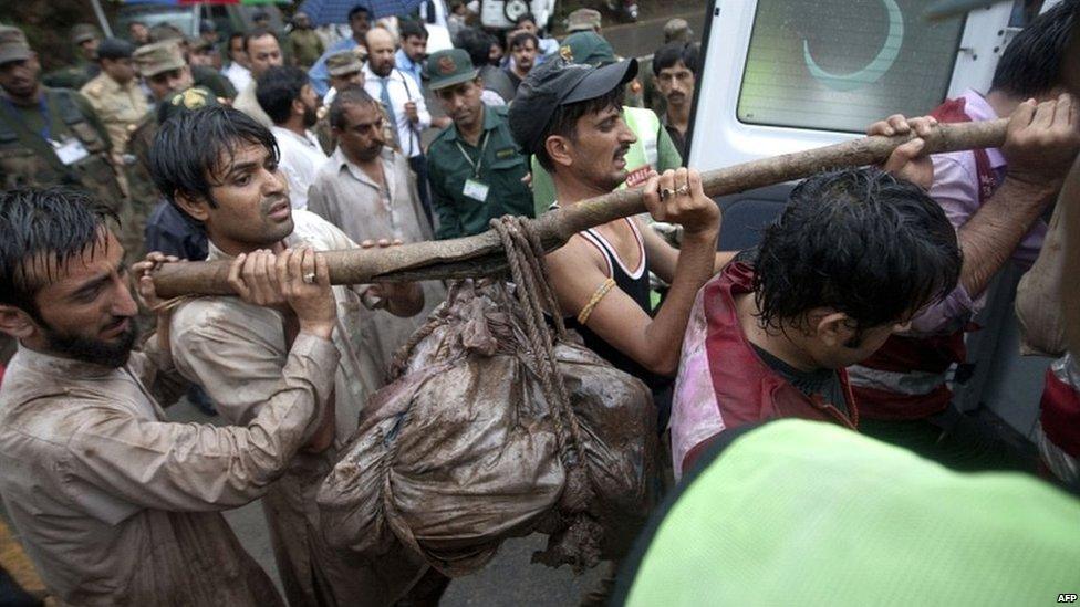 Pakistani aid workers carry the remains of victims of the crash