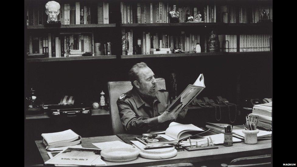 Castro in his office in Havana looking at photographs of the 1959 uprising.; Copyright Burt Glinn / Magnum Photos