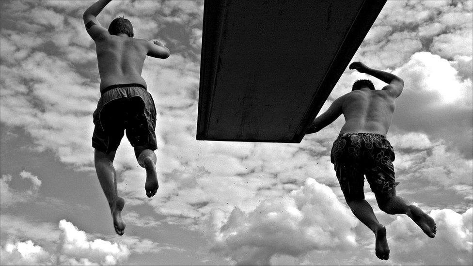 Two young men jump off a diving board