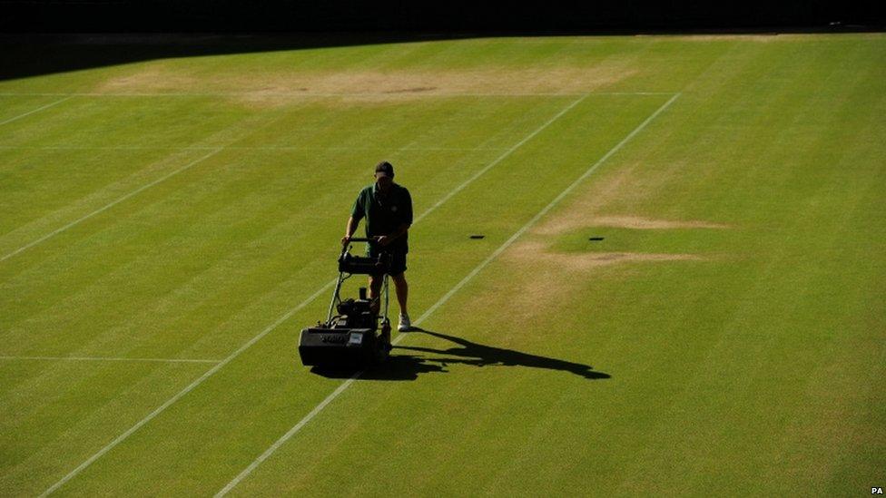 A man mows the grass on a court