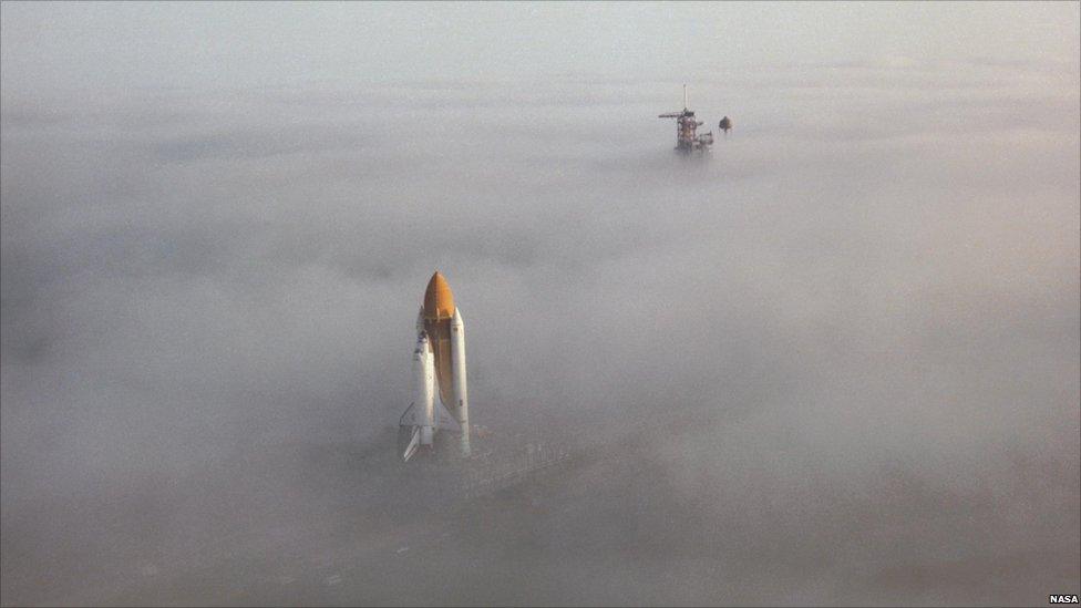 Space Shuttle Challenger moves through the fog on its way down the crawler way en route to Launch Pad 39A at Kennedy Space Center