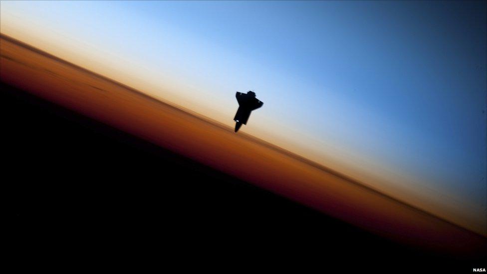 Space shuttle Endeavour is silhouetted against the backdrop of Earth's horizon