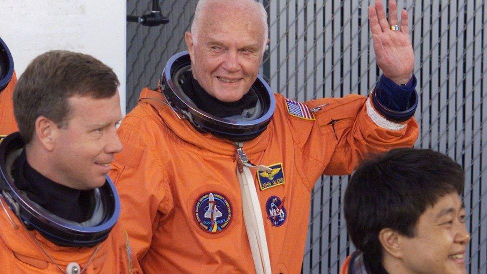 John Glenn waving and wearing his space gear