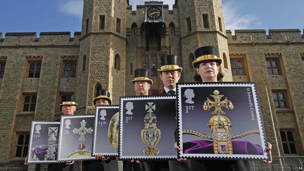 People holding some models of crown jewel stamps outside the Tower of London.