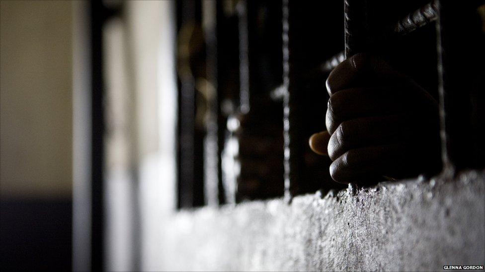 Prisoner's hands on the bars in his cell door, Liberia - 2011