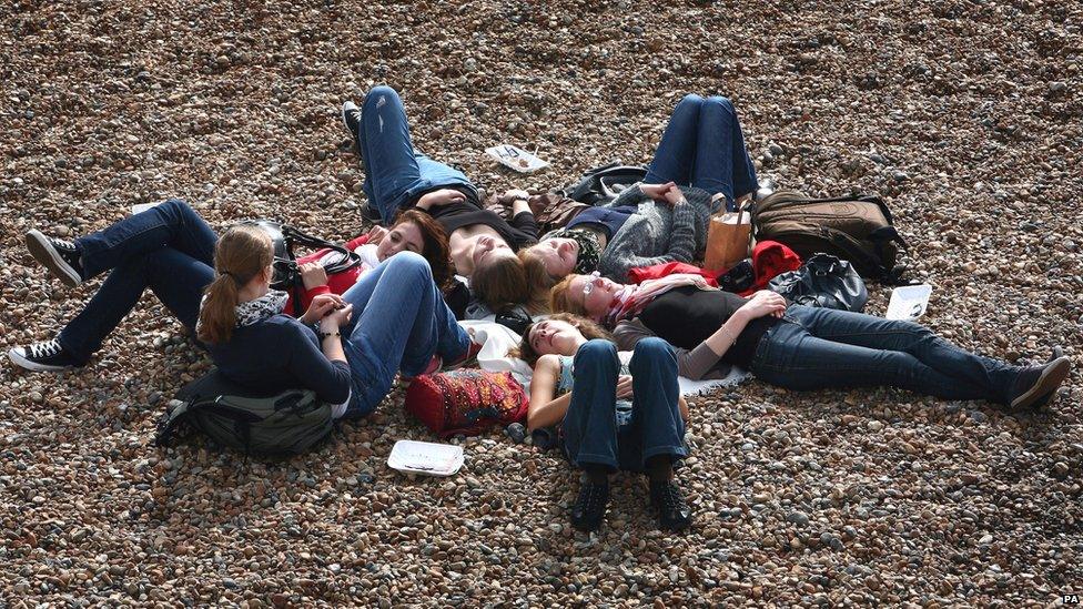 Friends relaxing in the warm weather on a beach in Brighton, East Sussex