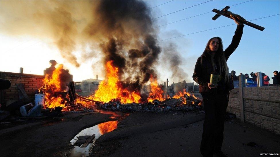 A traveller holds aloft a crucifix as a caravan burns on Dale Farm, near Basildon, east of London, on October 19, 2011