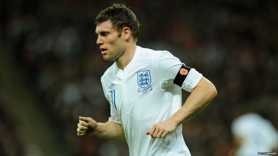 James Milner running on football pitch with black armband showing red poppy