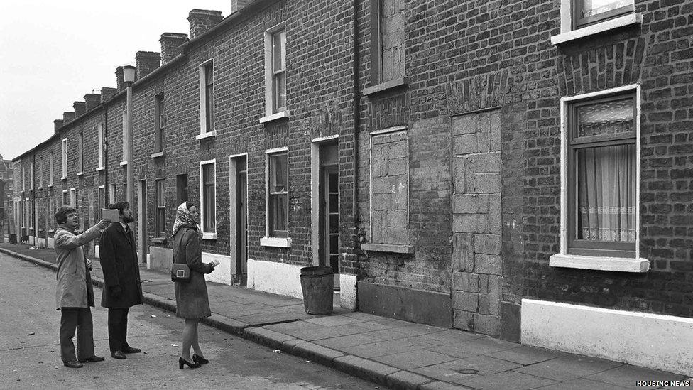 Three people examine terraced houses