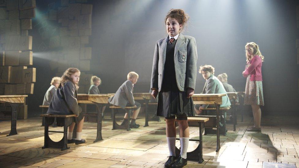 Nervous schoolgirl performs a song with classmates looking on.