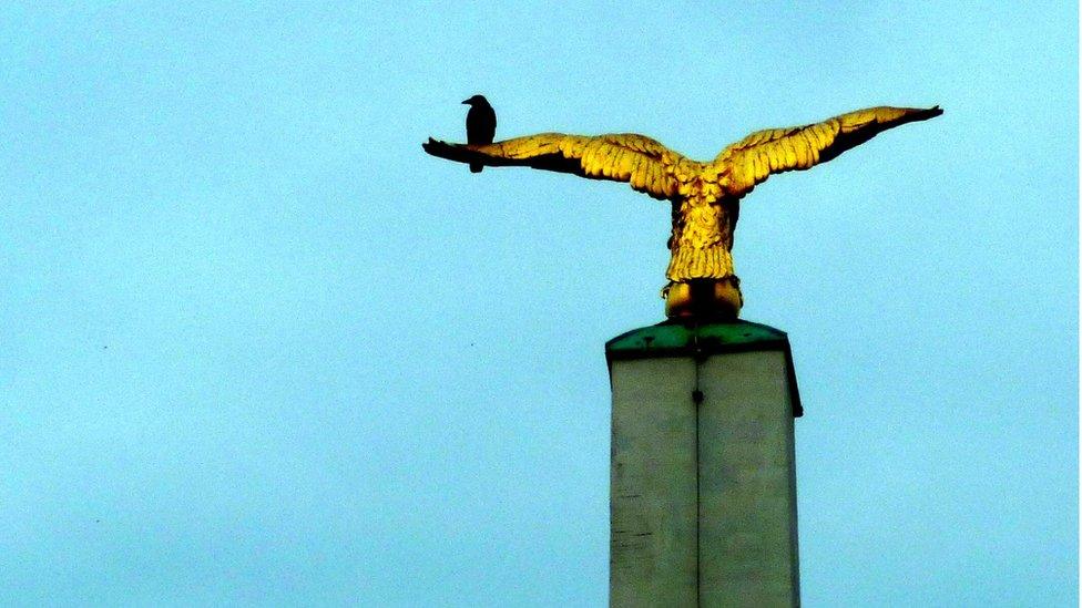 A crow on a statue of an eagle