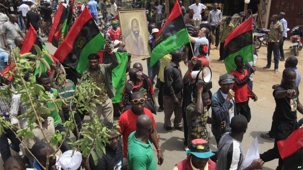 people holding a portrait of Col Ojukwu and waving Biafran flags