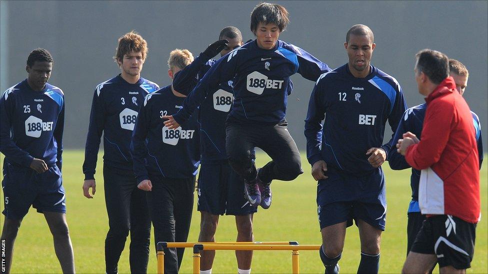 Bolton Wanderers players jump a hurdle during a training session at their Euxton training ground near Bolton