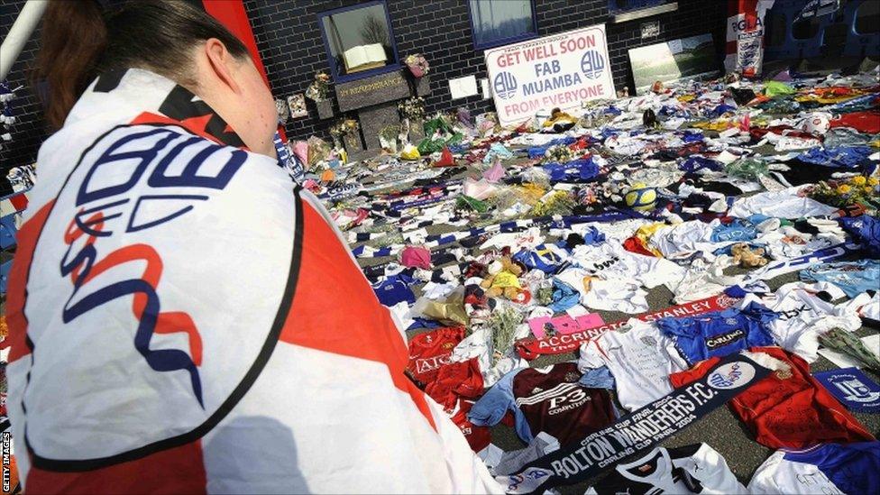 A woman looks at tributes to Bolton Wanderers' Fabrice Muamba outside their Reebok stadium