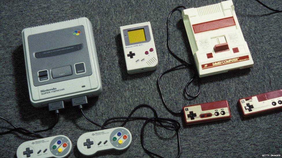 An old Nintendo Gameboy sits between an old Famicom and SuperFamicom console.