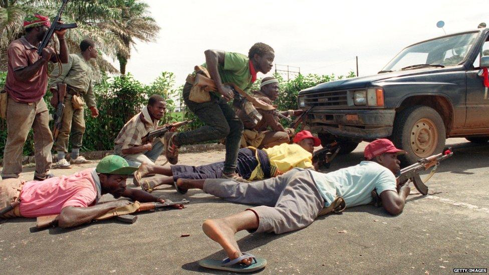 Rebels loyal to Charles Taylor of the National Patriotic Front of Liberia (NPFL) take position behind a truck 30 May 1990 in Monrovia during heavy clashes with the Armed Forces of Liberia (AFL) loyal to president Doe.