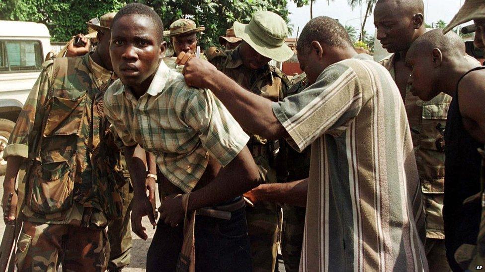 A Sierra Leone civilian is searched by West African peacekeepers part of ECOMOG forces at a gas station in Freetown, Sierra Leone to determine if he is a rebel fighter, 10 January 1999