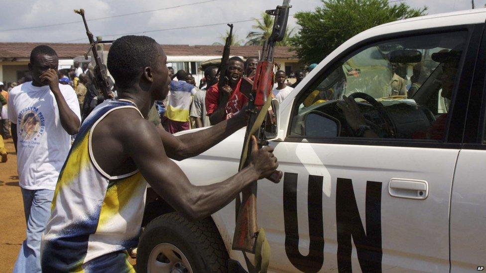 A fighter loyal to Charles Taylor tries to surrender arms to UN soldiers at Campe Schieffelin outside Monrovia, 7 September 2003